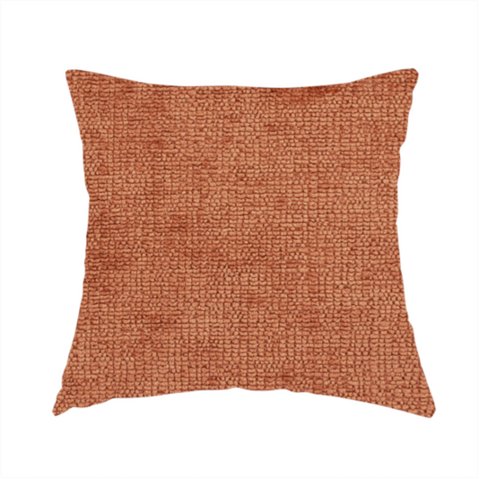 The fabric used to create this handmade cushion is a textured fabric swatch in a rich rust or burnt sienna colour. The material features a dense, uniform nubby weave with subtle dark undertones and shading, giving the soft surface a multi-tonal, warm appearance.