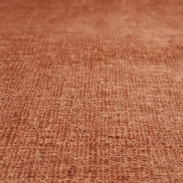 A textured fabric swatch in a rich rust or burnt sienna colour. The material features a dense, uniform nubby weave with subtle dark undertones and shading, giving the soft surface a multi-tonal, warm appearance.