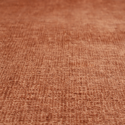 A textured fabric swatch in a rich rust or burnt sienna colour. The material features a dense, uniform nubby weave with subtle dark undertones and shading, giving the soft surface a multi-tonal, warm appearance.