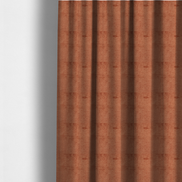 The fabric used to create these made-to-measure curtains is a textured fabric swatch in a rich rust or burnt sienna colour. The material features a dense, uniform nubby weave with subtle dark undertones and shading, giving the soft surface a multi-tonal, warm appearance.