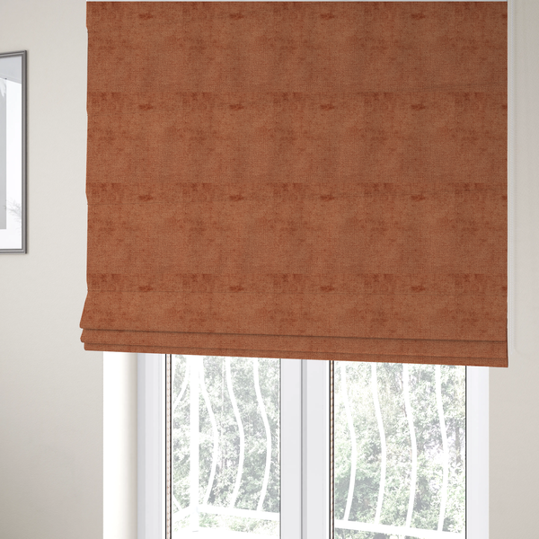 The fabric used to create these Roman blinds is a textured fabric swatch in a rich rust or burnt sienna colour. The material features a dense, uniform nubby weave with subtle dark undertones and shading, giving the soft surface a multi-tonal, warm appearance.