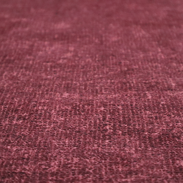 A textured fabric swatch in a rich berry red, burgundy, or mauve colour. The material features a dense, uniform nubby weave with subtle dark variations and shading, giving the soft surface a multi-tonal, deep appearance.