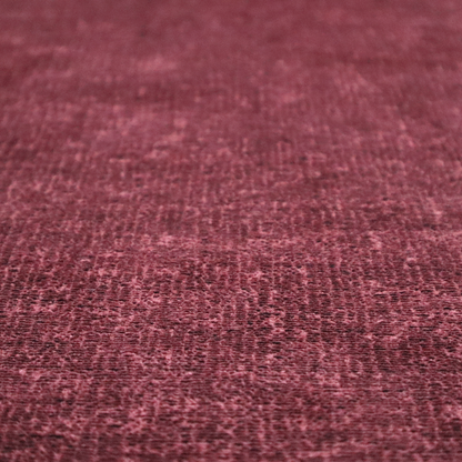A textured fabric swatch in a rich berry red, burgundy, or mauve colour. The material features a dense, uniform nubby weave with subtle dark variations and shading, giving the soft surface a multi-tonal, deep appearance.