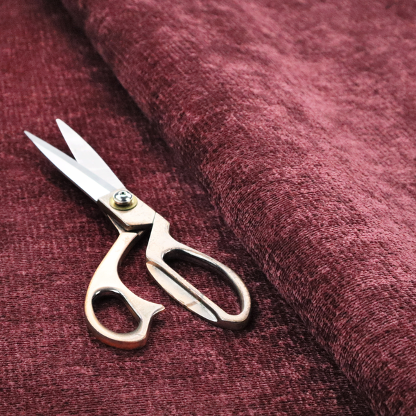 A textured fabric swatch in a rich berry red, burgundy, or mauve colour. The material features a dense, uniform nubby weave with subtle dark variations and shading, giving the soft surface a multi-tonal, deep appearance.