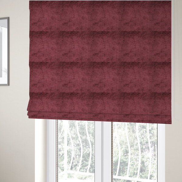 The fabric used to create these Roman blinds is a textured fabric swatch in a rich berry red, burgundy, or mauve colour. The material features a dense, uniform nubby weave with subtle dark variations and shading, giving the soft surface a multi-tonal, deep appearance.
