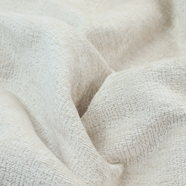 A textured fabric swatch in a soft cream, ivory, or natural off-white colour. The material features a dense, uniform nubby weave with subtle warm undertones, creating a cosy and clean appearance.