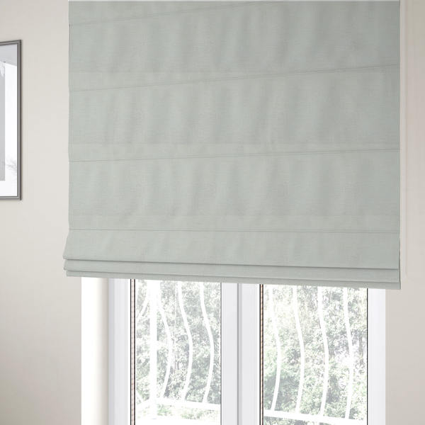 The fabric used to create these Roman blinds is a textured fabric swatch in a soft cream, ivory, or natural off-white colour. The material features a dense, uniform nubby weave with subtle warm undertones, creating a cosy and clean appearance.
