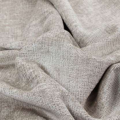A textured fabric swatch in a light, neutral taupe or sandy beige colour. The material features a dense, uniform nubby weave with subtle horizontal striations and warm grey undertones, creating a soft, multi-tonal appearance.