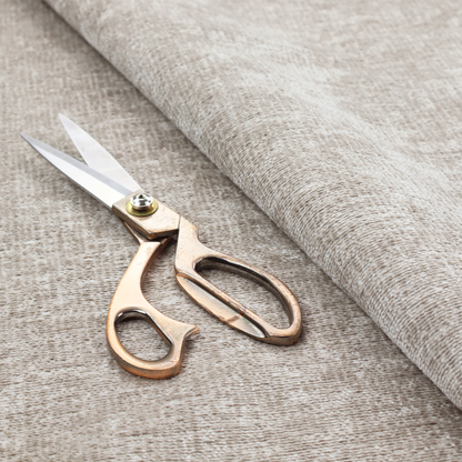 A textured fabric swatch in a light, neutral taupe or sandy beige colour. The material features a dense, uniform nubby weave with subtle horizontal striations and warm grey undertones, creating a soft, multi-tonal appearance.