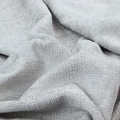 A textured fabric swatch in a very pale, light grey or silver colour. The material features a dense, uniform nubby weave with subtle neutral undertones, creating a soft, clean, and modern appearance.