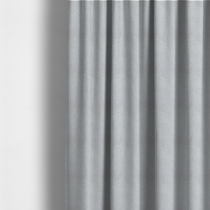 The fabric used to create these made-to-measure curtains is a textured fabric swatch in a very pale, light grey or silver colour. The material features a dense, uniform nubby weave with subtle neutral undertones, creating a soft, clean, and modern appearance.