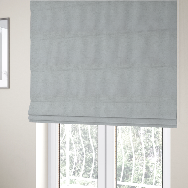 The fabric used to create these Roman blinds is a textured fabric swatch in a very pale, light grey or silver colour. The material features a dense, uniform nubby weave with subtle neutral undertones, creating a soft, clean, and modern appearance.
