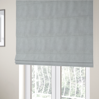 The fabric used to create these Roman blinds is a textured fabric swatch in a very pale, light grey or silver colour. The material features a dense, uniform nubby weave with subtle neutral undertones, creating a soft, clean, and modern appearance.