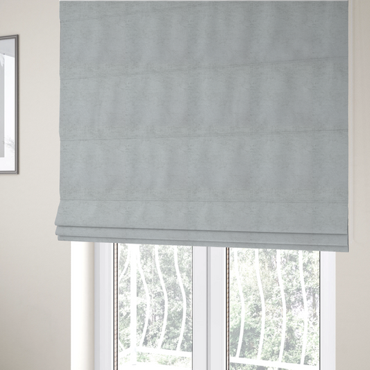 The fabric used to create these Roman blinds is a textured fabric swatch in a very pale, light grey or silver colour. The material features a dense, uniform nubby weave with subtle neutral undertones, creating a soft, clean, and modern appearance.