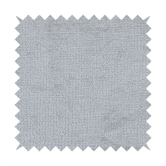 A textured fabric swatch in a cool, light-to-medium grey or stone colour. The material features a dense, uniform nubby weave with subtle horizontal shadowing, creating a soft, contemporary matte finish.
