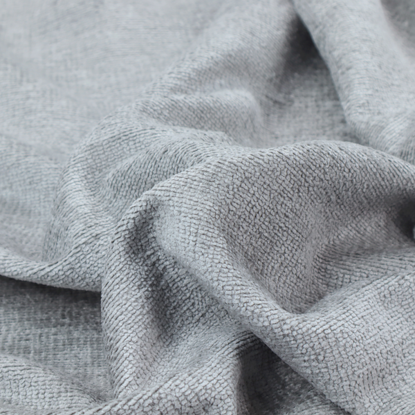 A textured fabric swatch in a cool, light-to-medium grey or stone colour. The material features a dense, uniform nubby weave with subtle horizontal shadowing, creating a soft, contemporary matte finish.