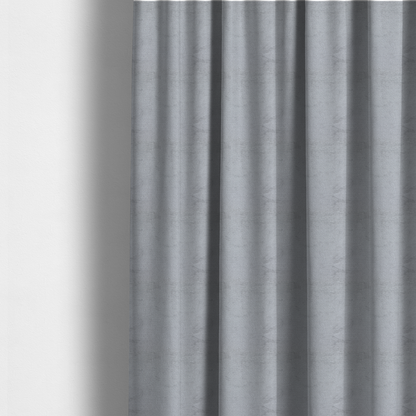 The fabric used to create these made-to-measure curtains is a textured fabric swatch in a cool, light-to-medium grey or stone colour. The material features a dense, uniform nubby weave with subtle horizontal shadowing, creating a soft, contemporary matte finish.