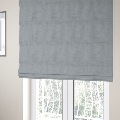 The fabric used to create these Roman blinds is a textured fabric swatch in a cool, light-to-medium grey or stone colour. The material features a dense, uniform nubby weave with subtle horizontal shadowing, creating a soft, contemporary matte finish.