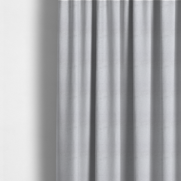 The fabric used to create these made-to-measure curtains is a textured fabric swatch in a very light, icy grey or pale ash colour. The material features a dense, uniform nubby weave with bright neutral tones, creating a clean, crisp, and contemporary appearance.