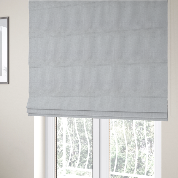 The fabric used to create these Roman blinds is a textured fabric swatch in a very light, icy grey or pale ash colour. The material features a dense, uniform nubby weave with bright neutral tones, creating a clean, crisp, and contemporary appearance.