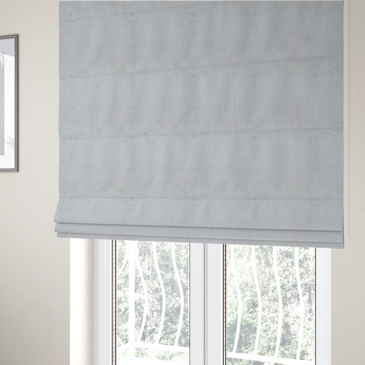 The fabric used to create these Roman blinds is a textured fabric swatch in a very light, icy grey or pale ash colour. The material features a dense, uniform nubby weave with bright neutral tones, creating a clean, crisp, and contemporary appearance.