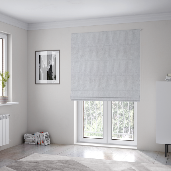 The fabric used to create these Roman blinds is a textured fabric swatch in a very light, icy grey or pale ash colour. The material features a dense, uniform nubby weave with bright neutral tones, creating a clean, crisp, and contemporary appearance.