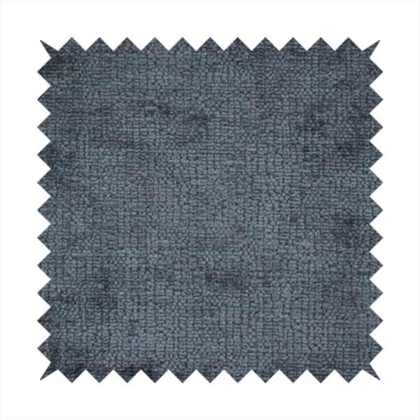 a textured fabric swatch in a dark charcoal or graphite grey colour. The material features a dense, uniform nubby weave with deep, moody undertones and subtle dark shadowing, creating a rich, contemporary appearance.