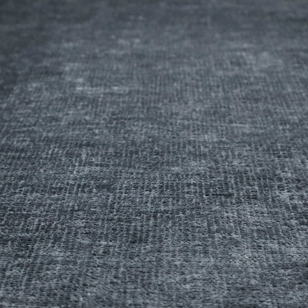 a textured fabric swatch in a dark charcoal or graphite grey colour. The material features a dense, uniform nubby weave with deep, moody undertones and subtle dark shadowing, creating a rich, contemporary appearance.