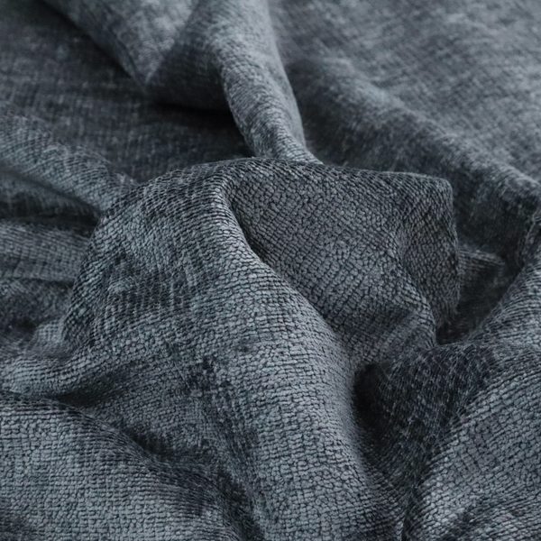 a textured fabric swatch in a dark charcoal or graphite grey colour. The material features a dense, uniform nubby weave with deep, moody undertones and subtle dark shadowing, creating a rich, contemporary appearance.