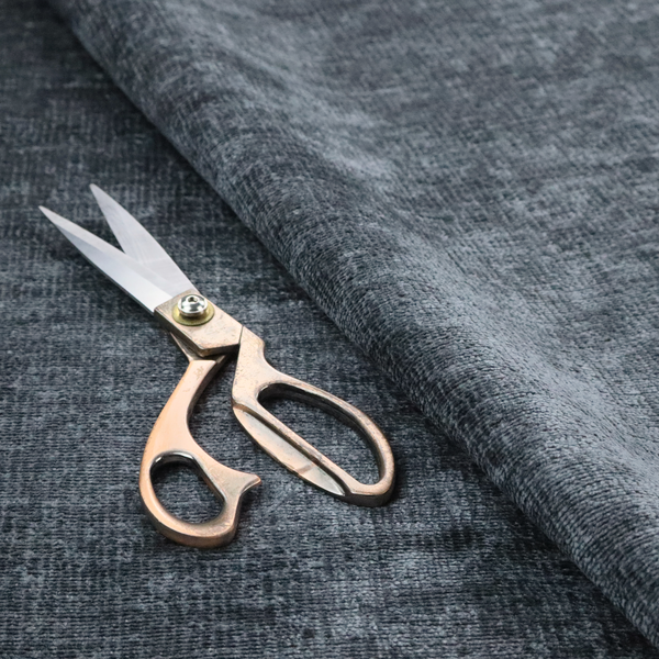 a textured fabric swatch in a dark charcoal or graphite grey colour. The material features a dense, uniform nubby weave with deep, moody undertones and subtle dark shadowing, creating a rich, contemporary appearance.