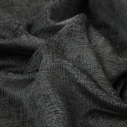 A textured fabric swatch in a very dark anthracite or charcoal grey colour. The material features a dense, uniform nubby weave with deep, almost black shading variations, creating a rich, moody, and sophisticated appearance.