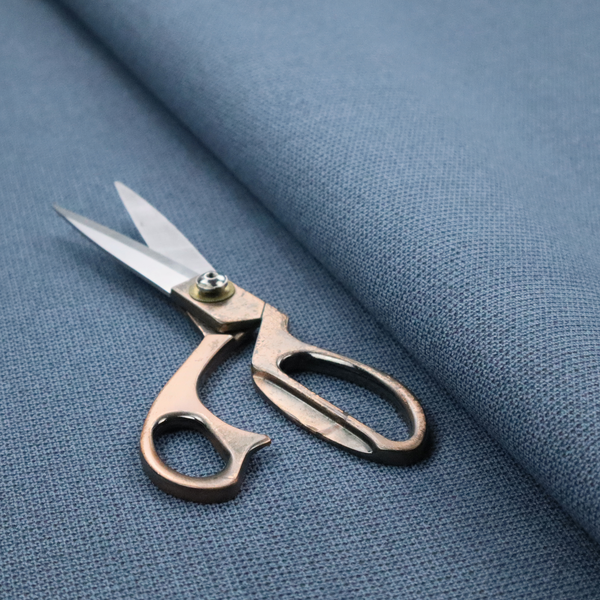 A textured denim blue fabric with a tight, uniform cross-weave pattern.