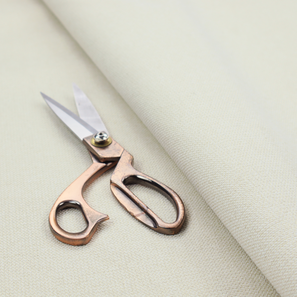 A textured cream-coloured fabric with a tight, uniform cross-weave.