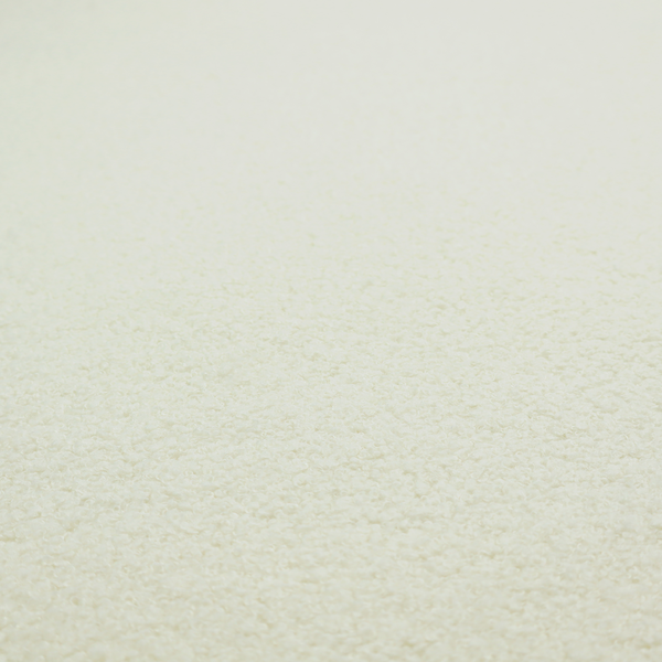 A textured cream-coloured bouclé upholstery fabric.