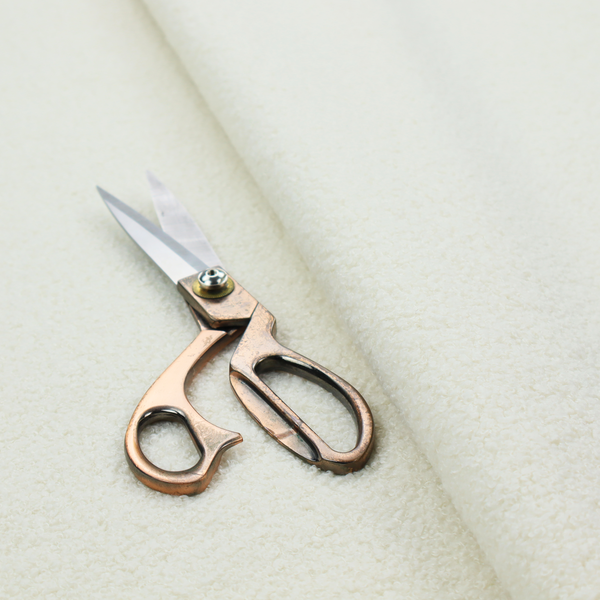 A textured cream-coloured bouclé upholstery fabric.
