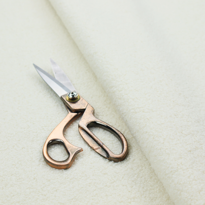 A textured cream-coloured bouclé upholstery fabric.