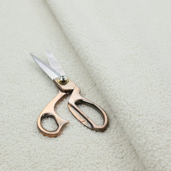 A textured beige or oatmeal bouclé upholstery fabric.