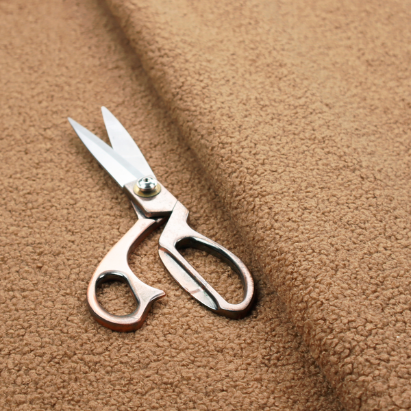 A textured camel brown bouclé upholstery fabric.