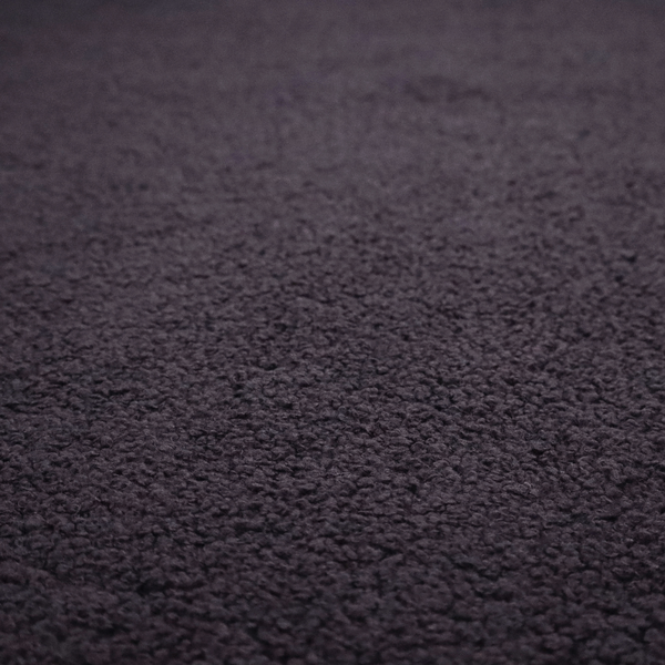 A textured dark plum or deep charcoal purple bouclé upholstery fabric.