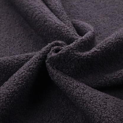 A textured dark plum or deep charcoal purple bouclé upholstery fabric.