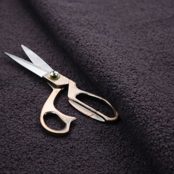 A textured dark plum or deep charcoal purple bouclé upholstery fabric.