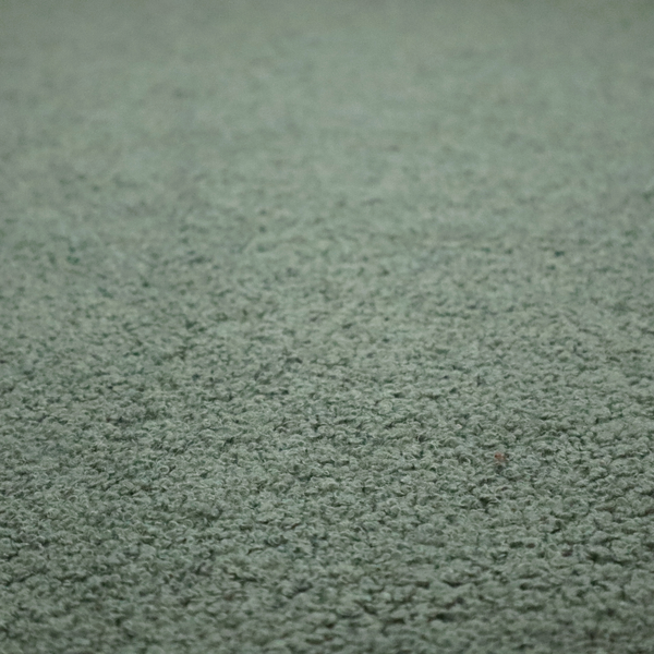 A textured sage green or muted jade bouclé upholstery fabric.