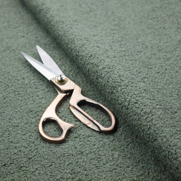 A textured sage green or muted jade bouclé upholstery fabric.