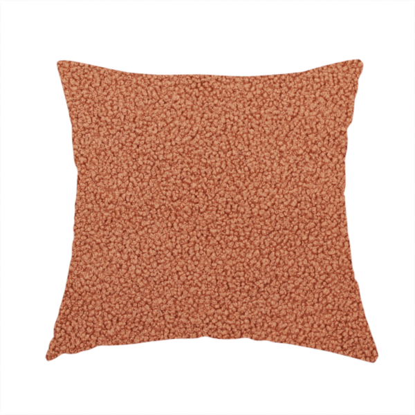 The fabric used to create this handmade cushion is a terracotta or rust-orange boucle fabric texture.