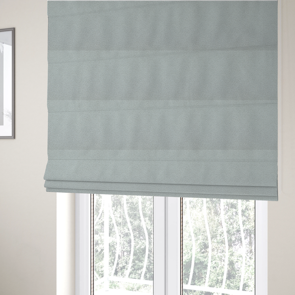 The fabric used to create these Roman blinds is a light grey or pale ice-blue boucle fabric texture.