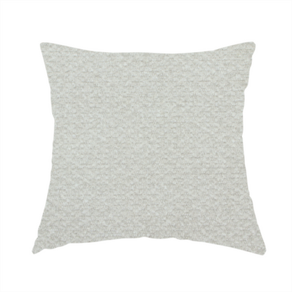 The fabric used to create this handmade cushion is a swatch of light grey, textured upholstery fabric.