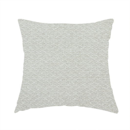 The fabric used to create this handmade cushion is a swatch of light grey, textured upholstery fabric.