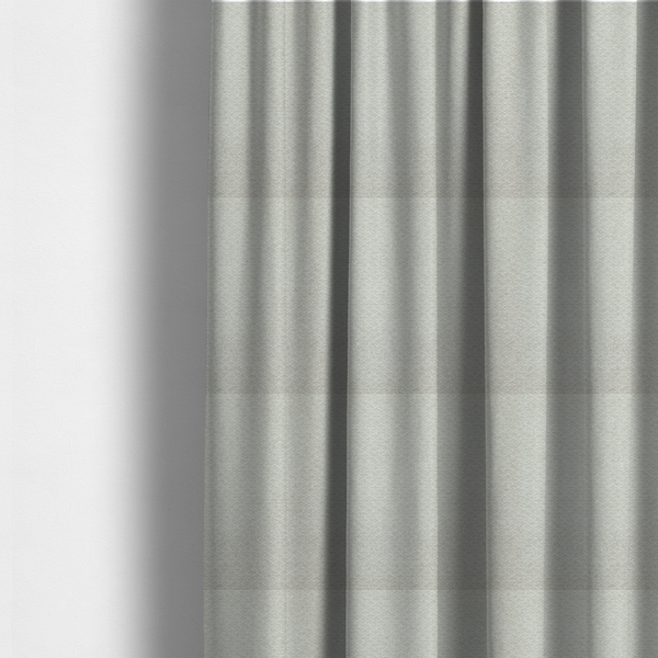The fabric used to create these made-to-measure curtains is a swatch of light grey, textured upholstery fabric.