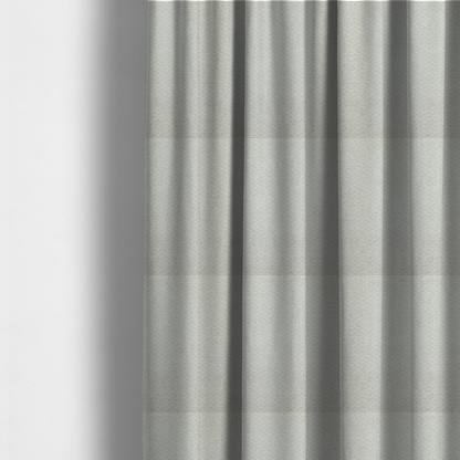 The fabric used to create these made-to-measure curtains is a swatch of light grey, textured upholstery fabric.