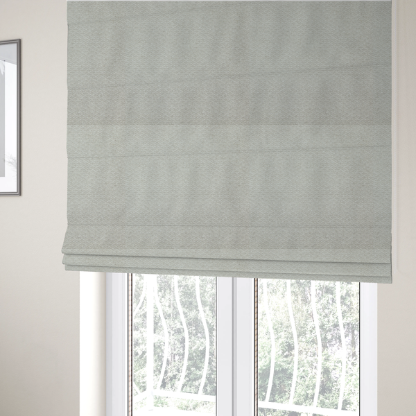 The fabric used to create these Roman blinds is a swatch of light grey, textured upholstery fabric.
